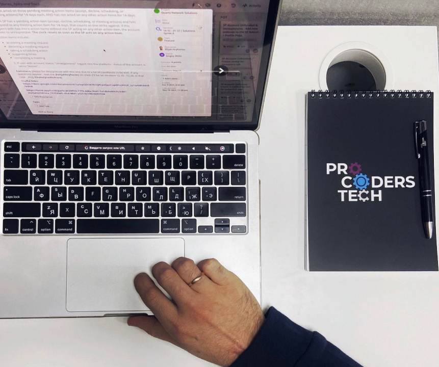 Open laptop and a ProCoders notebook on a table